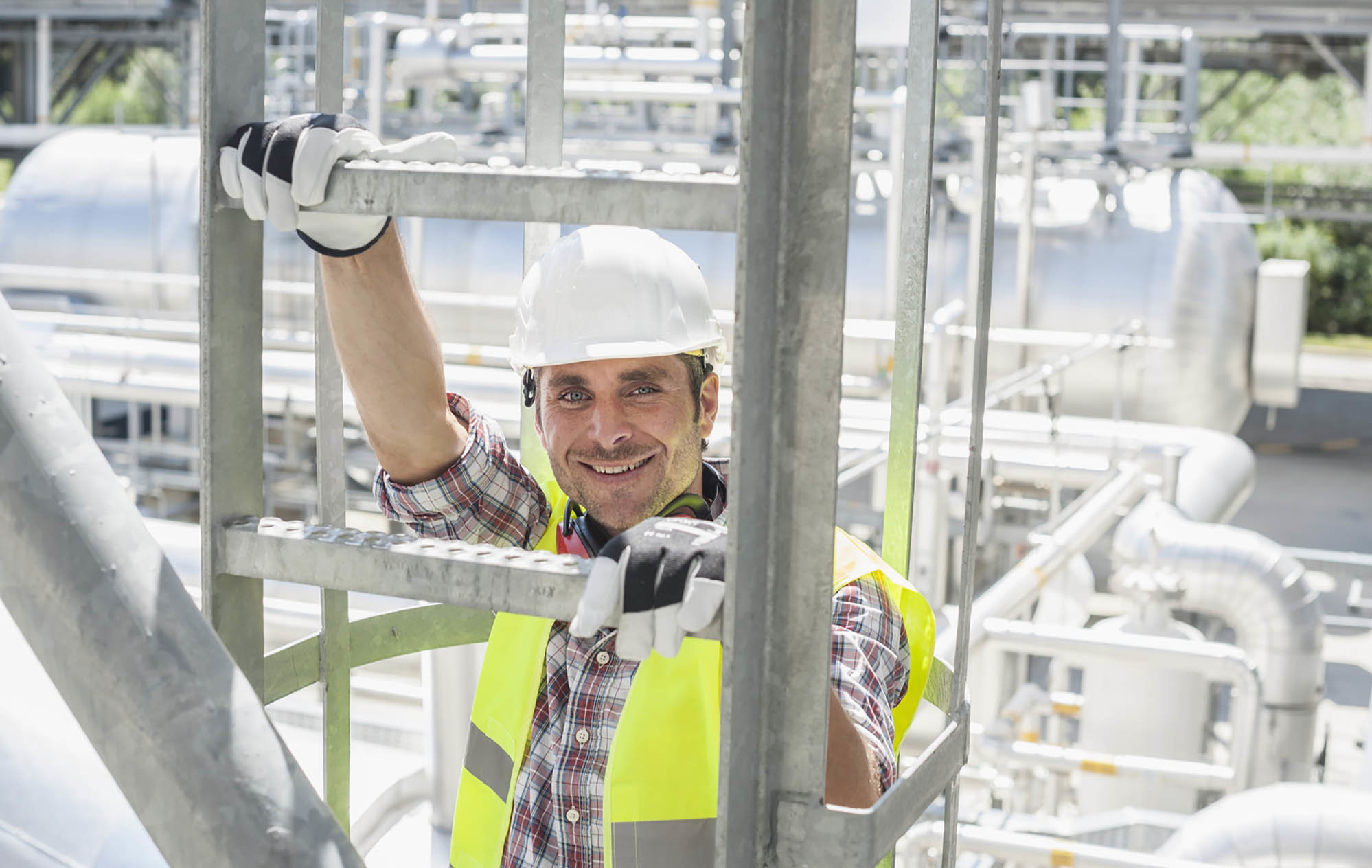 Mann klettert auf Leiter in Industrieanlage